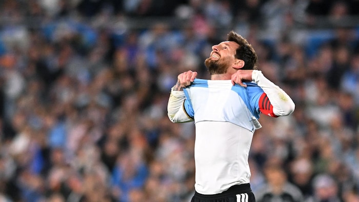 Un joueur de soccer lève son chandail et sourit en regardant le ciel.