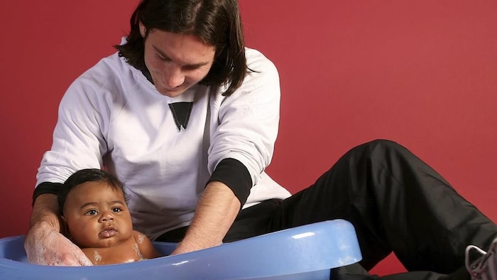 Un jeune Lionel Messi donne le bain à un bébé.