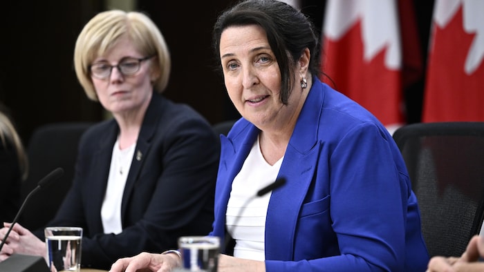 Lise Maisonneuve s'adresse aux médias en point de presse et Carla Qualtrough l'observe en arrière.