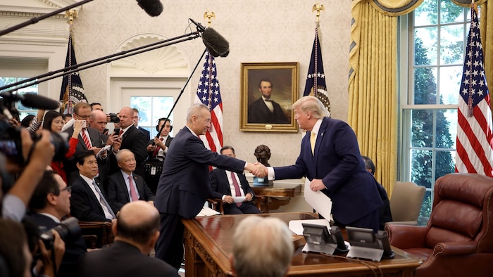 Liu He et Donald Trump se serrent la main dans le bureau ovale de la Maison-Blanche.