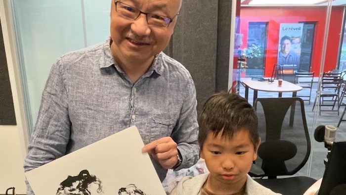 劉昕手持一幅作品和兒子合影。