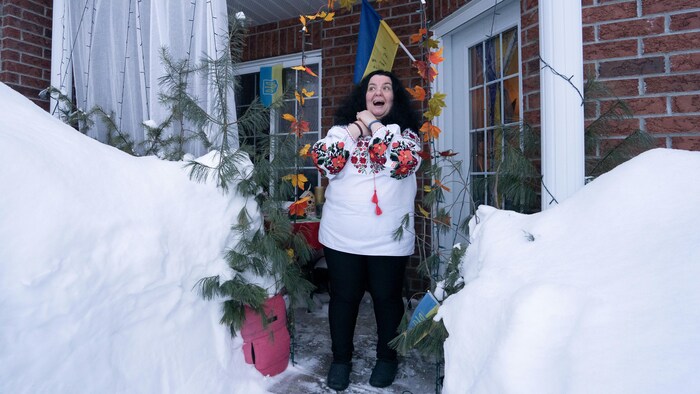 Une femme joint ses mains et sourit en regardant la neige.