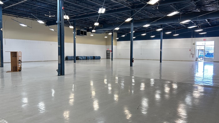 Une vaste salle vide avant l'arrivée des installations de gymnastique.