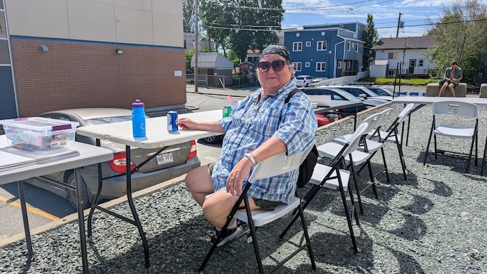 Mme Fournier est assise à une table avec une boisson gazeuse.