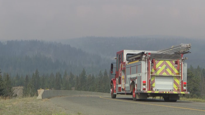 Un paysage enfumé avec un camion de pompier dans la moitié droite du cadre.