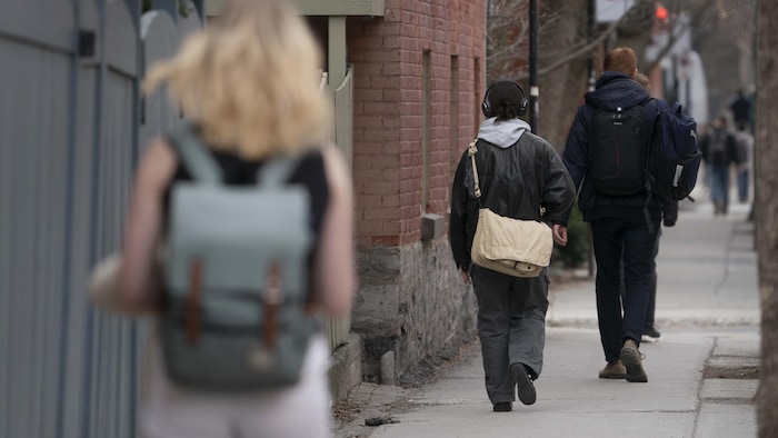 Des étudiants vus de dos marchent dans une rue de Montréal.