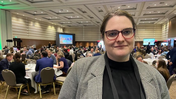 Julia Woodhall-Melnik devant des tables dans une salle de conférence.