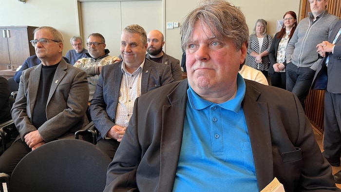 Michel Savard est assis au milieu du public. 