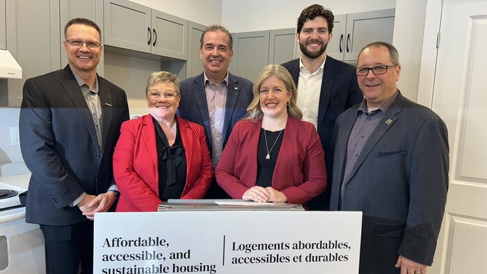 Des gens à un lutrin qui sourient à la caméra.