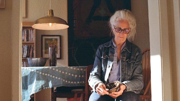 Portrait de l'artiste dans son salon, un pot en céramique dans les mains. 