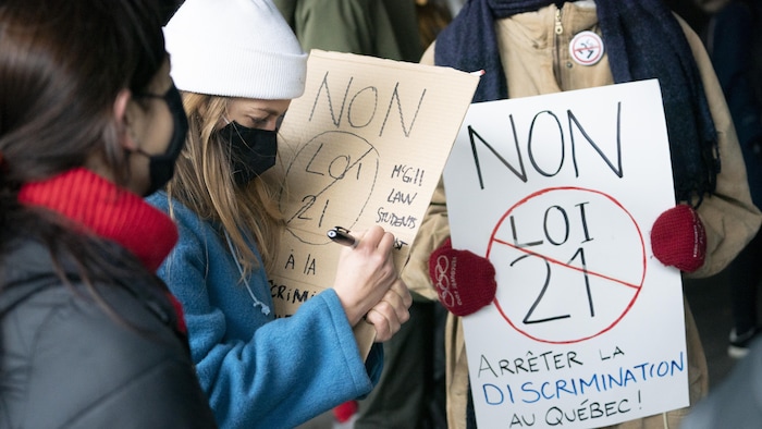 Des femmes tiennent des pancartes contre la loi 21.
