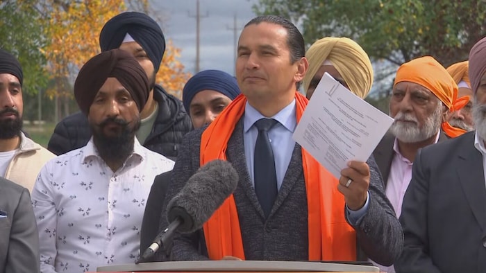 Wab Kinew lors d'une conférence de presse avec des hommes politiques portant des signes religieux visibles.