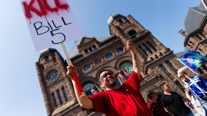 Des manifestants et des membres de la communauté scandent des slogans et brandissent des pancartes tout en écoutant les orateurs lors d’une manifestation contre le projet de loi 5, devant l’Assemblée législative de l’Ontario à Queen’s Park.