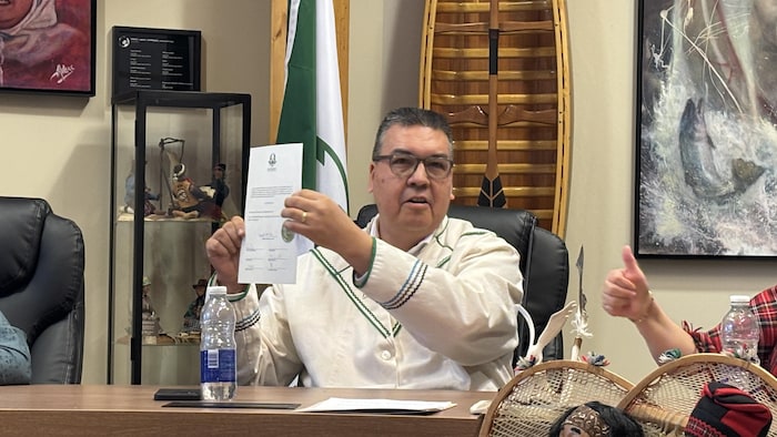 Un homme assis brandit une feuille de papier.