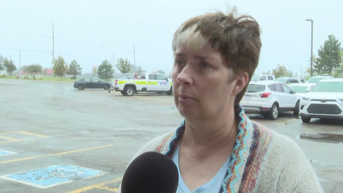 Lois Landry répond aux questions d'un journaliste dans un stationnement. 