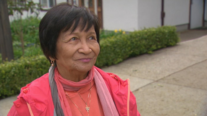 Une femme habillée en rose avec de cheveux noirs courts.