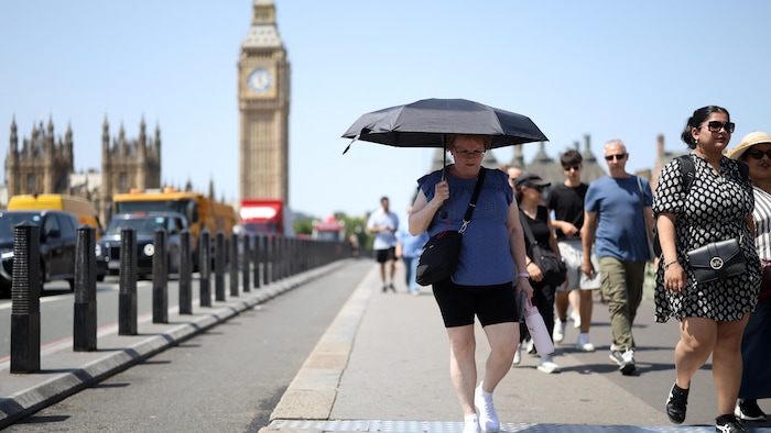 Une femme se protège du soleil avec un parasol à Londres, le 23 juin 2026.