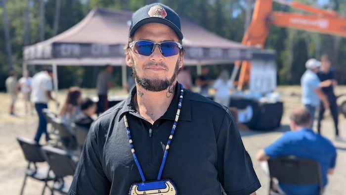 Steven Polson, portant lunettes de soleil et casquette, regarde la caméra sans vraiment sourire.