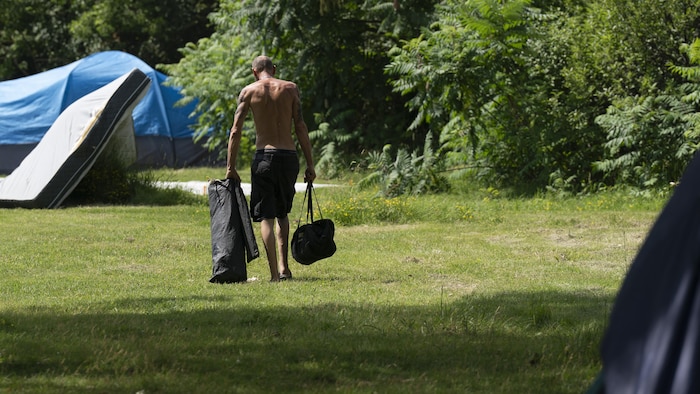 Un résident du campement sur le bord du fleuve, à Longueuil, vu de dos.