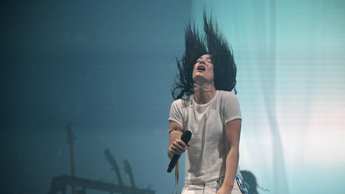 La chanteuse est sur scène les cheveux dressés dans les airs. 