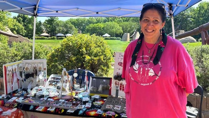 Une femme debout sourit à l'intérieur d'un kiosque où des perles sont exposées, le 21 juin 2025 à La Fourche à Winnipeg.