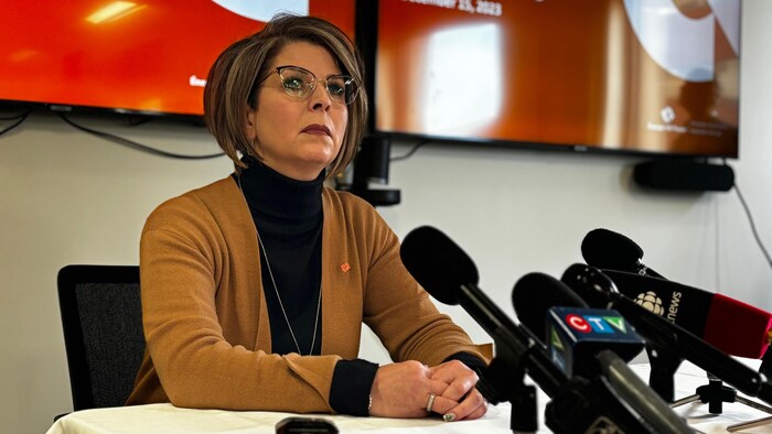 Une femme donne une conférence de presse. 