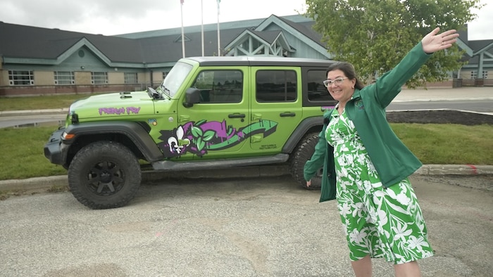 Lori Ratté montre son véhicule vert, arborant les deux fleur du drapeau franco-ontarien.