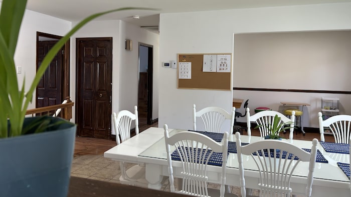 Une table avec plusieurs chaises autour, au centre d'une salle à manger. 