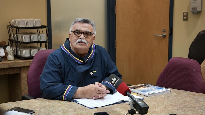 Un homme est assis devant un micro et répond à des questions de journalistes lors d'un huit clos budgétaire l’Assemblée législative du Nunavut, à Iqaluit, le 24 février 2025.