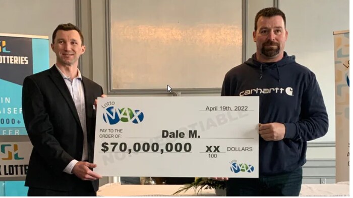 Dale McEwen reçoit son chèque de 70 millions d’un représentant de Sask Lotteries. 
