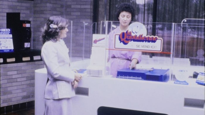 Un kiosque de Loto-Québec avec une employée et une cliente au comptoir.