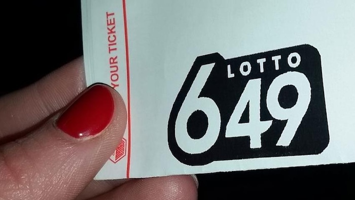 Billet de Lotto 6/49 tenu par une main de femme.