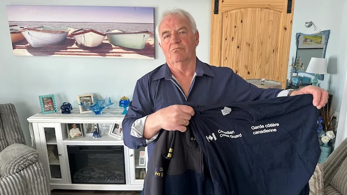 Lou Callaghan, chez lui, montre son gilet de la Garde côtière.