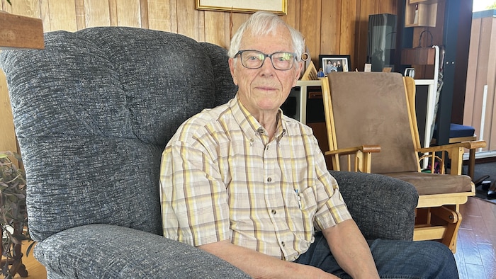Portrait de Louis Arsenault assis dans un fauteuil du salon.