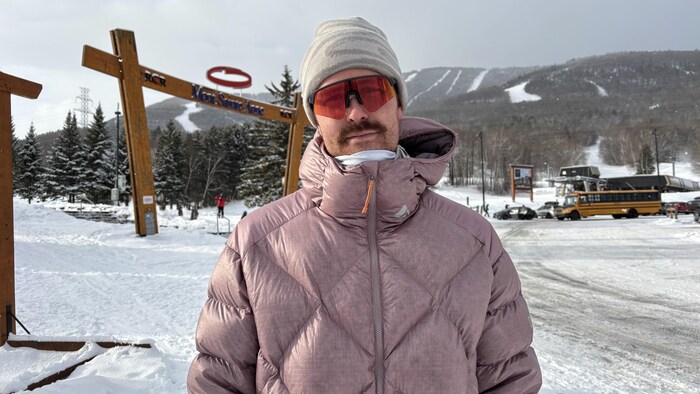 Un homme prend la pose devant le Mont-Sainte-Anne.