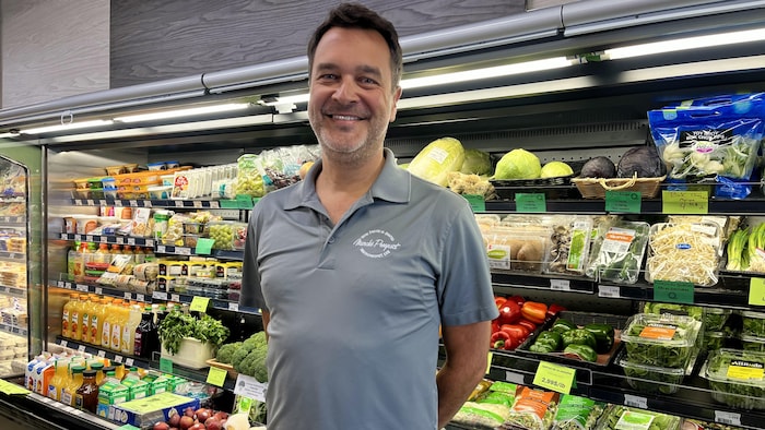 Louis Delisle devant une étagère de légumes.