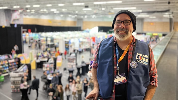 Louis-Éric Gagnon pose dans les gradins, le Salon du livre en arrière-plain.