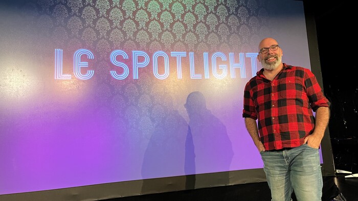 Louis-Éric Gagnon pose devant un écran portant le nom Le Spotlight, souriant.