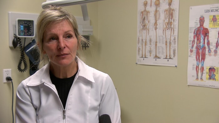 La Dre Louise Caron (plan rapproché) dans un furniture de médecin. Elle porte une chemise blanche de médecin.