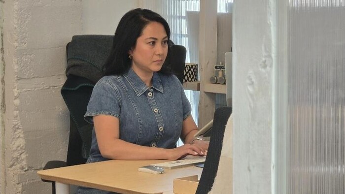 Lourdes Juan, une femme assise à un bureau, un écran d'ordinateur en face d'elle.