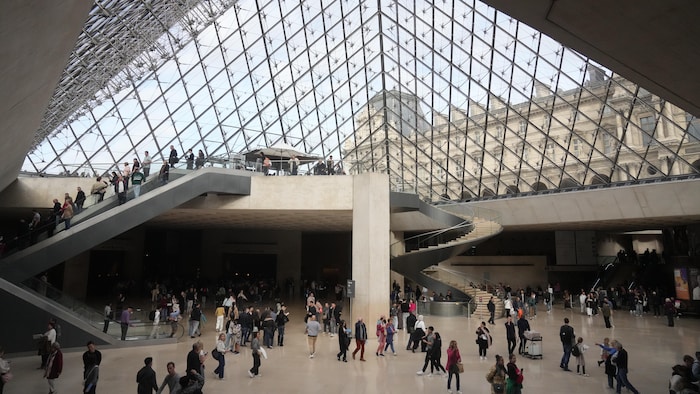Des visiteurs marchent dans le grand hall du Louvre.