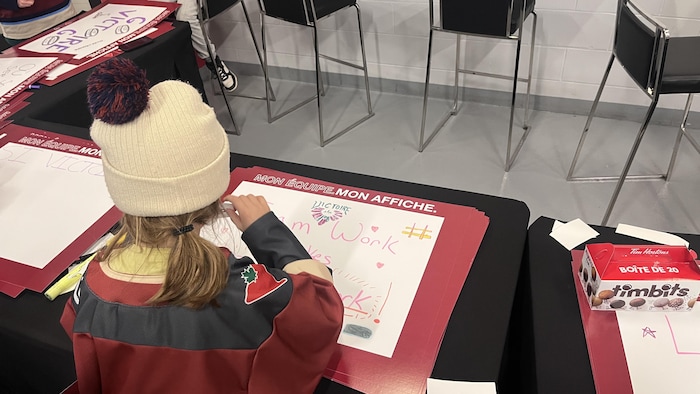 Une jeune fille en train de dessiner sur une affiche.