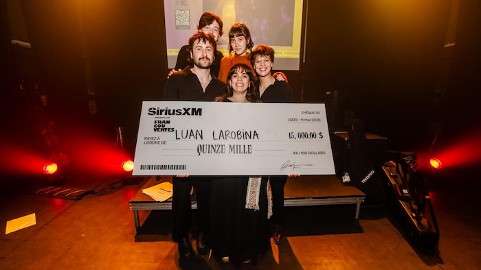 La chanteuse et son groupe posent avec un chèque géant au montant de 15 000 dollars. 