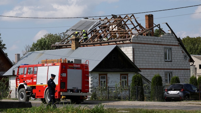Un policier se tient debout tandis que des pompiers interviennent sur le toit détruit d'une maison, après que des drones russes ont violé l'espace aérien polonais lors d'une attaque contre l'Ukraine, certains ayant été abattus par la Pologne avec le soutien de ses alliés de l'OTAN, à Wyryki-Wola, dans la voïvodie de Lublin, en Pologne.