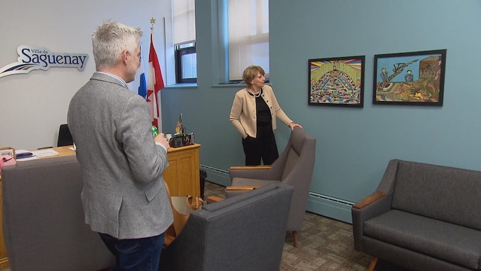 Deux personnes admirent des tableaux dans un bureau.