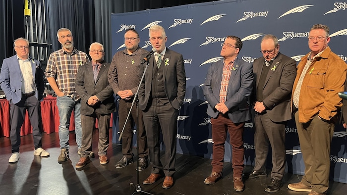 Huit hommes regroupés sur une scène. 