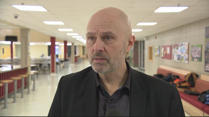 Un homme en entrevue à l'intérieur d'une école.