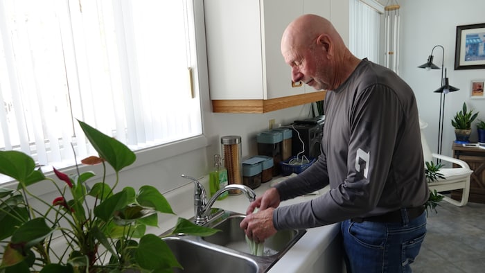 Luc Charest en train de faire la vaisselle dans sa cuisine.