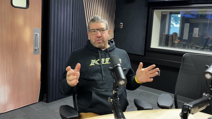 Un homme en entrevue en studio.
