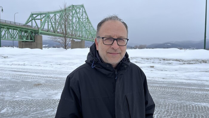 Luc Couturier sourit à la caméra, le pont J.C. Van Horne dernière lui.